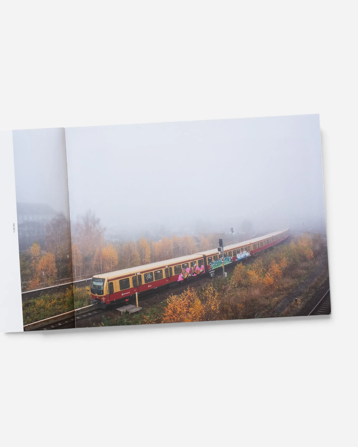 Astrofat Farbzüge photography book open to a page showing a graffiti-covered Berlin S-Bahn train in foggy autumn scenery.